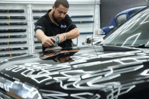 polishing a black car’s hood to remove surface scratches at Clayton Care in Dubai.
