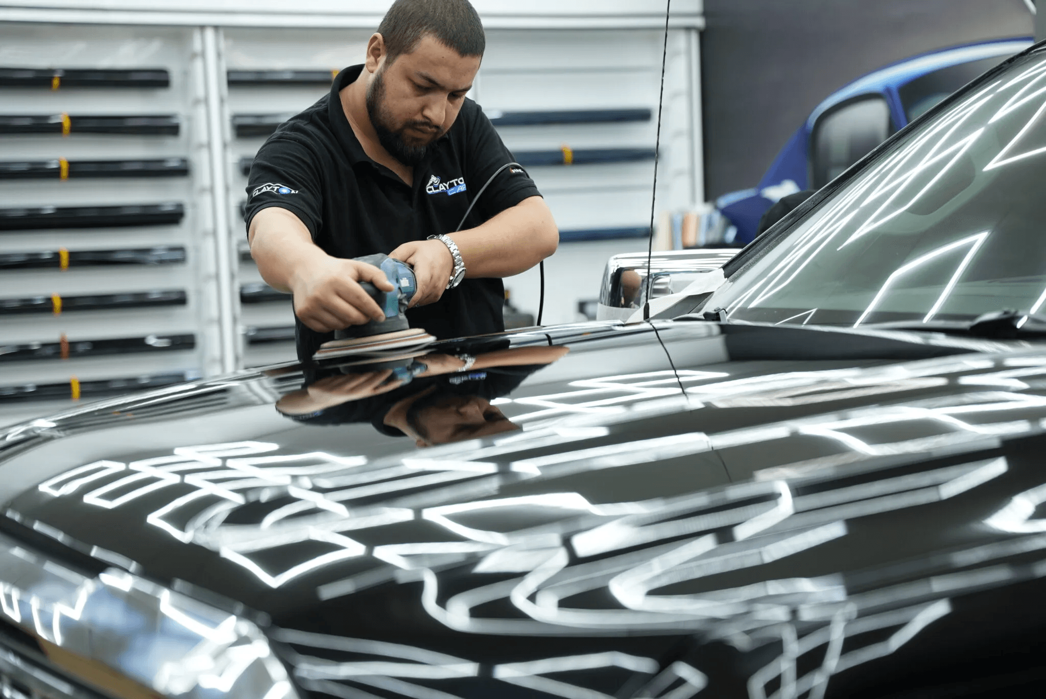 polishing a black car’s hood to remove surface scratches at Clayton Care in Dubai.